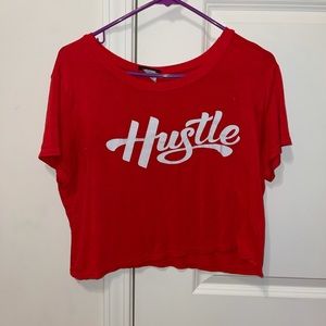 off the shoulder red “hustle” shirt.